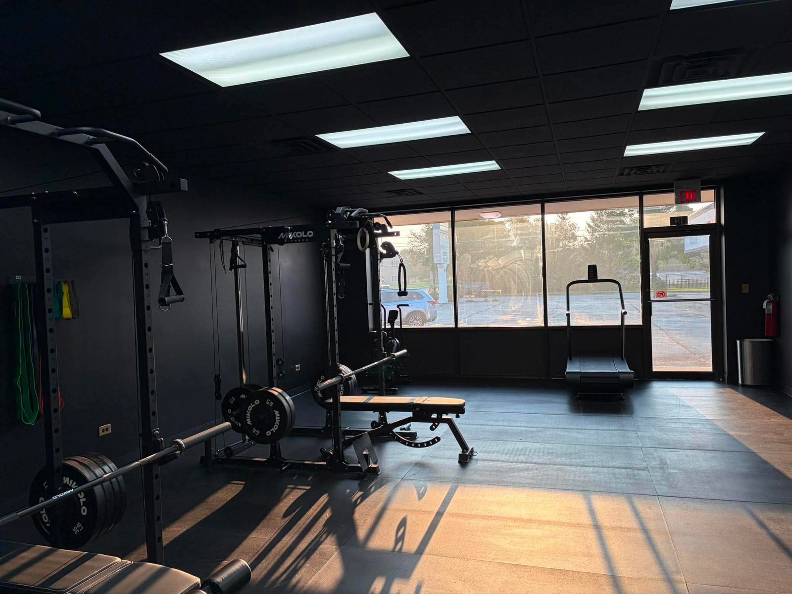 Sunlit open training floor with rack, bench, and treadmill at Odyssey Strength & Recovery
